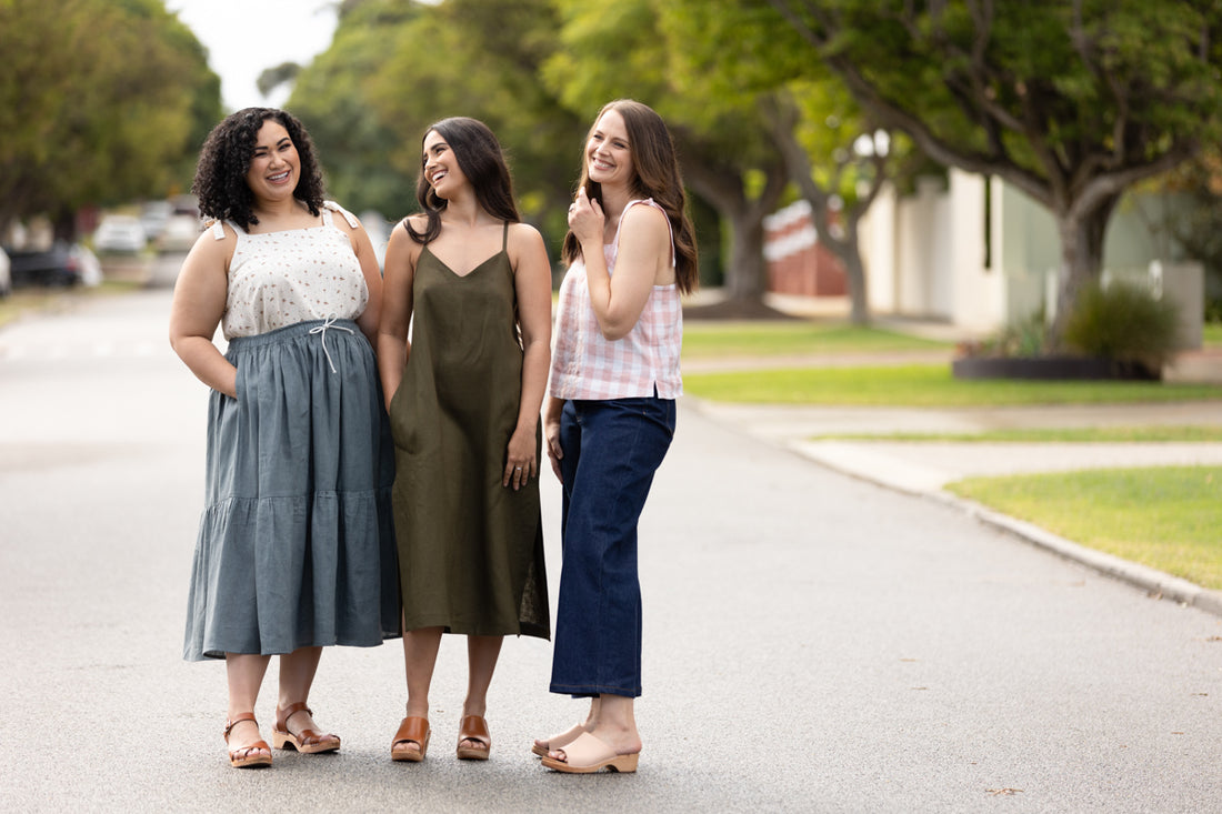 Three models laugh together, two wearing Marri camisoles and one wearing a Marri dress